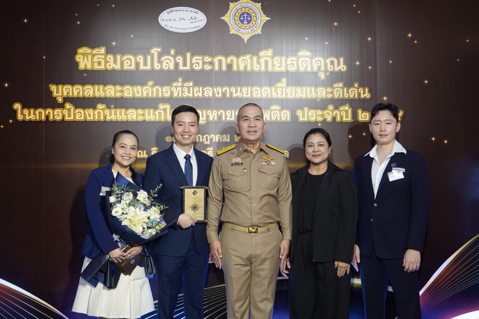 นพ.พิชญุตม์ ถ่ายภาพร่วมกับผู้ได้รับรางวัลบนเวที